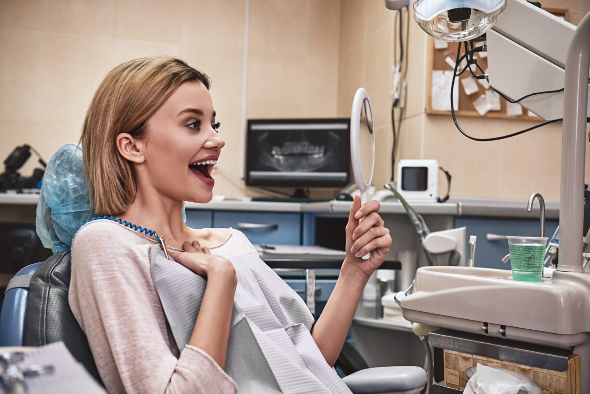 Zachwycona pacjentka ogląda efekty leczenia w lusterku – leczenie kanałowe Ez-Dent Oleśnica